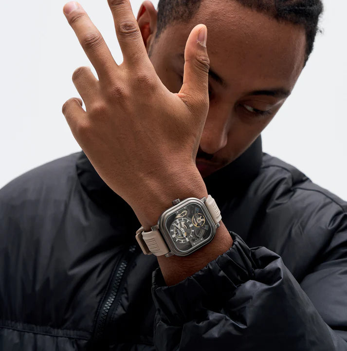Luxury skeleton watch with carbon fiber case, bold motorsport design, and beige strap on wrist