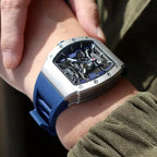 Motorsport-inspired skeleton watch with blue strap and bold tonneau case on wrist