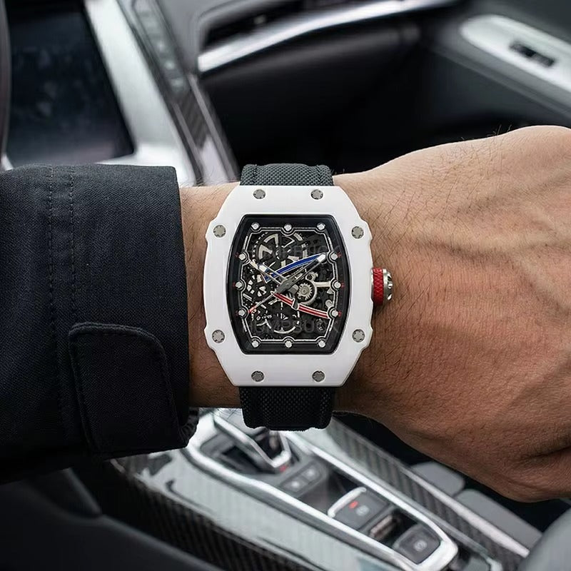 Luxury skeleton watch with white case, black strap, red crown, worn in car — motorsport-inspired design