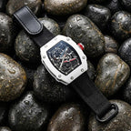 Luxury sport watch with skeleton dial, carbon fiber case, and black strap on wet stones — motorsport-inspired design