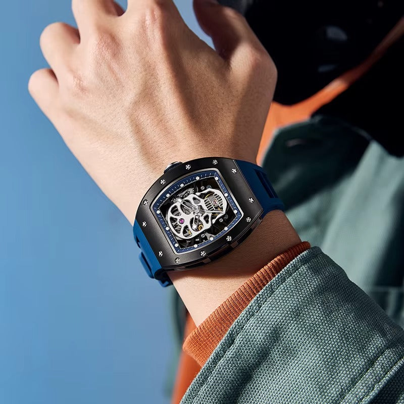 Luxury skeleton dial racing-inspired watch with blue strap and tonneau case on wrist