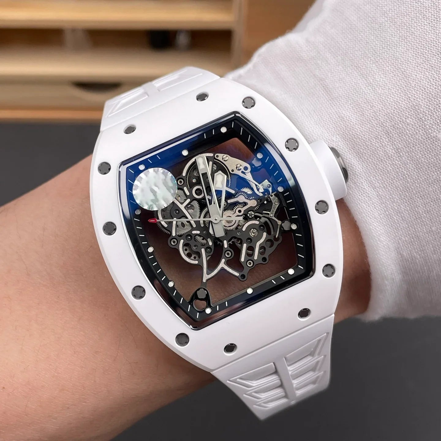 White tonneau-shaped skeleton watch with exposed mechanical movement, inspired by motorsport design