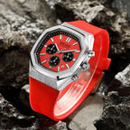 Luxury motorsport-inspired chronograph watch with red dial, red strap, and steel case on rocks