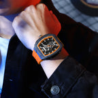 Motorsport-inspired skeleton watch with orange strap and bold tonneau case on wrist