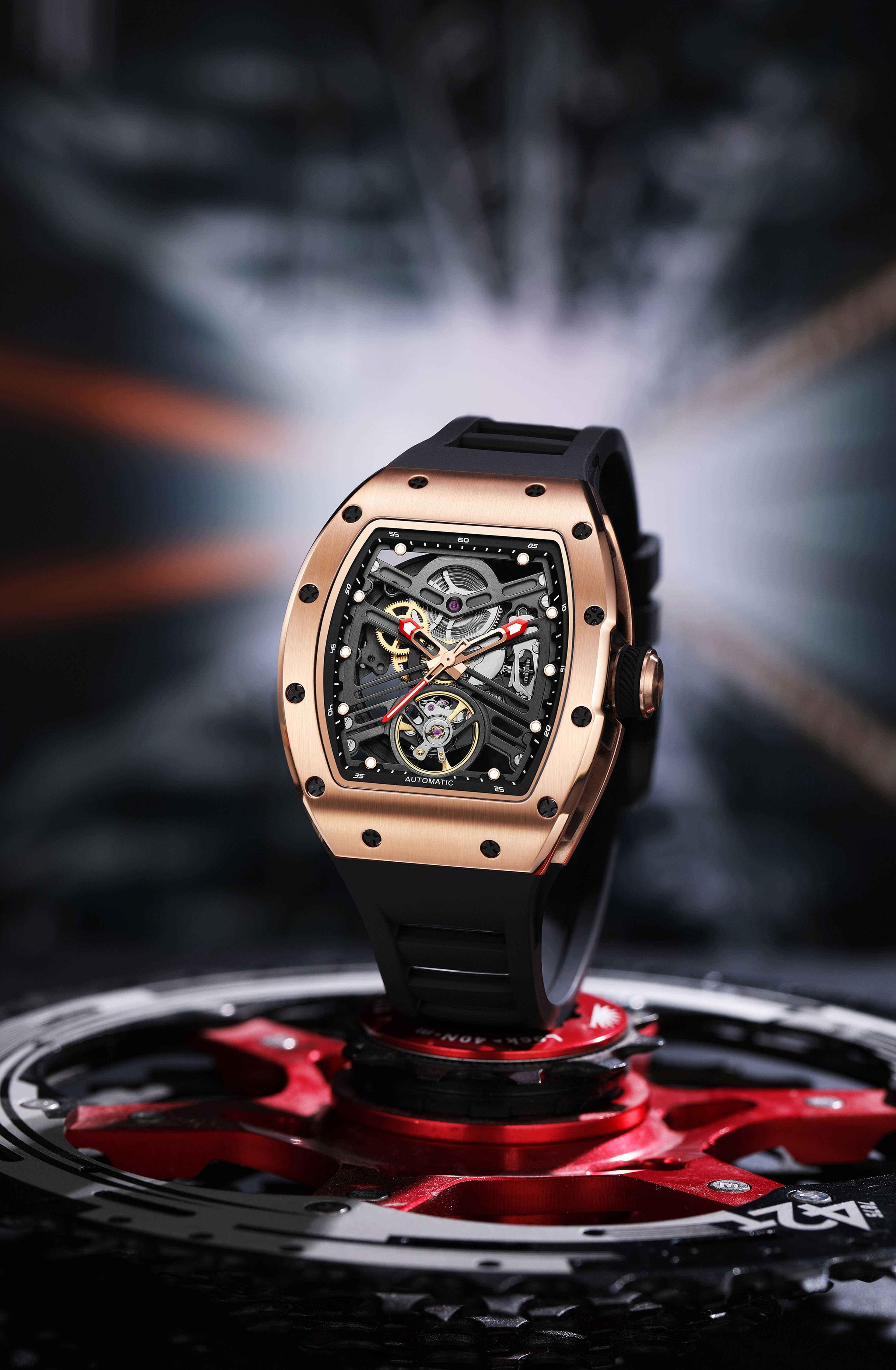 Luxury motorsport-inspired skeleton watch with rose gold case and black rubber strap on gear